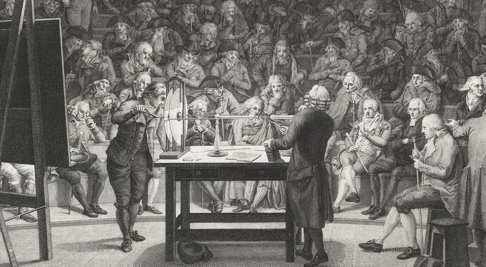 Black-and-white engraving of a lecture hall where a demonstrator sparks an electrical apparatus on a table before rows of seated, wigged spectators.