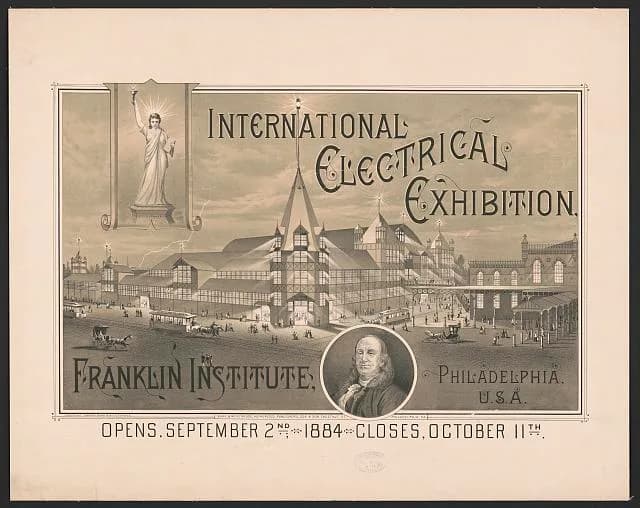 Sepia-toned poster reading 'International Electrical Exhibition, Franklin Institute, Philadelphia U.S.A., Opens September 2nd 1884, Closes October 11th', with an illustrated exhibition hall, a torch-bearing statue, and a circular portrait of Benjamin Franklin.